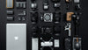 Collection of camera equipment and accessories on a dark surface with a laptop.